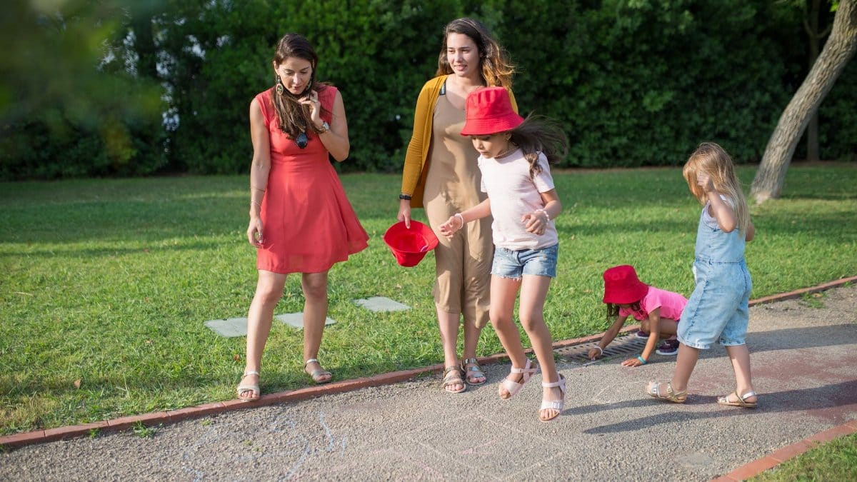 A joyous family experience in a lush Portugal park, featuring playful activities between young girls and adults.