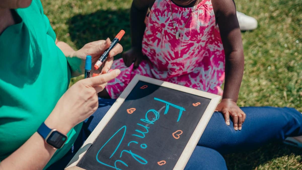 Mother and child bonding outdoors with a chalkboard, emphasizing family values.