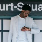 A fashionable man in a white blazer checks his wristwatch at Court Square station.