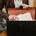 Close-up of a businesswoman organizing files in a black box in an office setting.