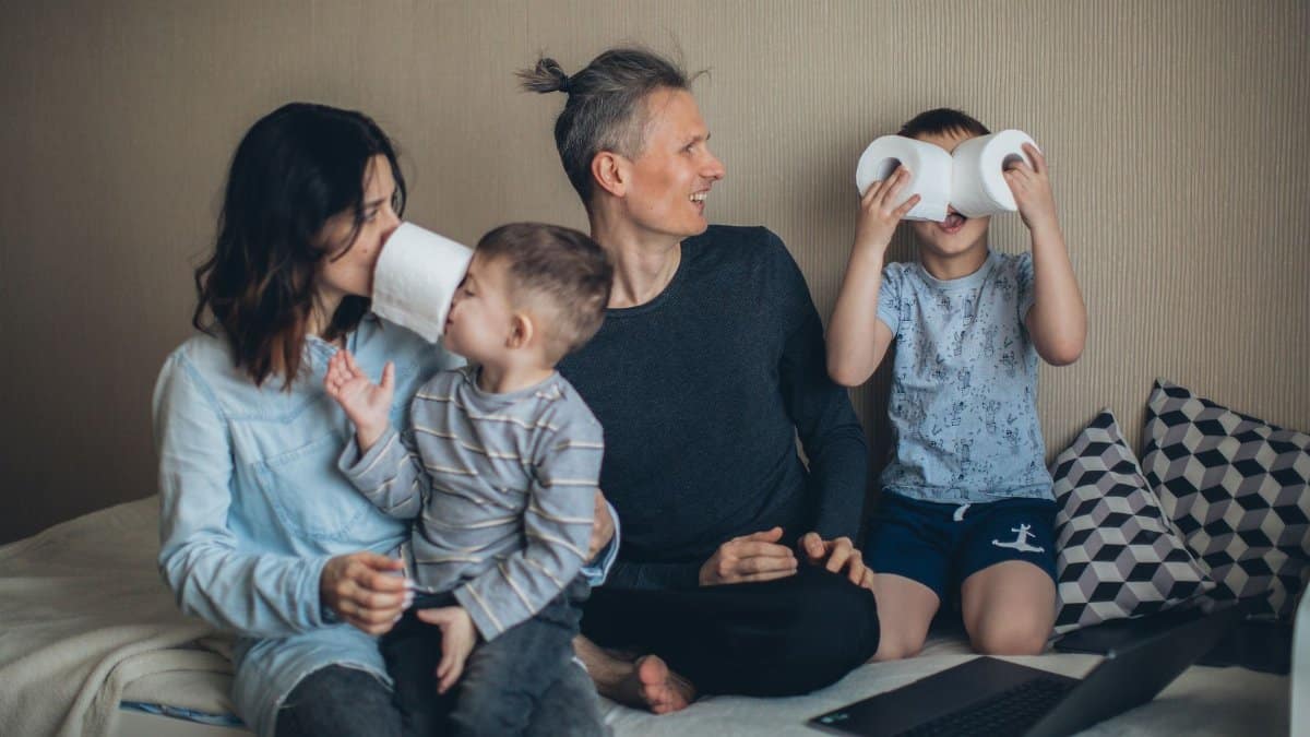 A family enjoying a playful moment at home using toilet paper rolls creatively while relaxing together.