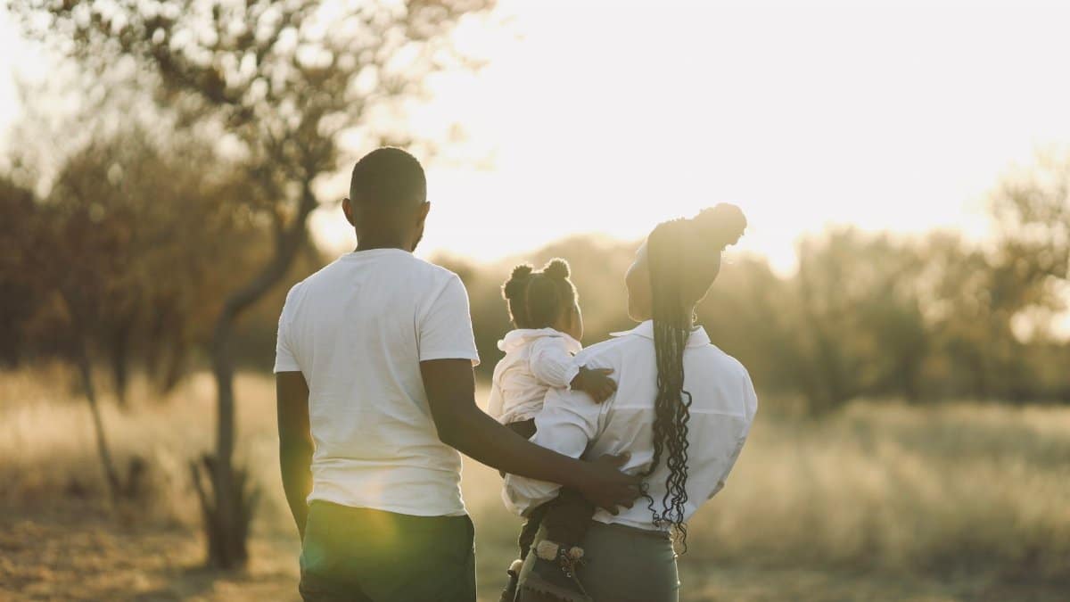 A family enjoys a peaceful walk in a sunlit park during fall, embodying warmth and togetherness.