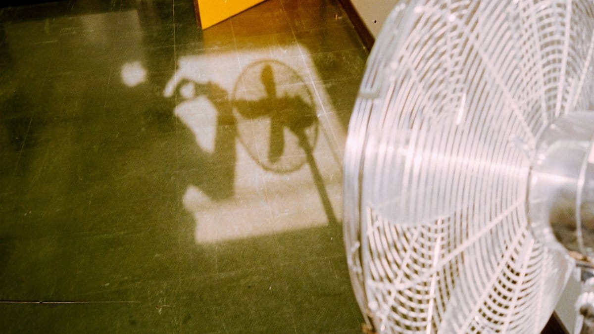 Interesting shadow of a fan casting on a green floor with an open door.