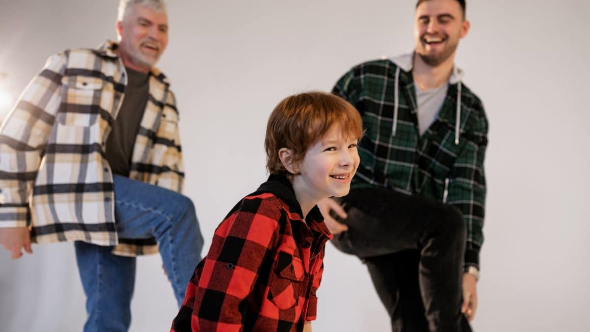 A joyful moment shared among three generations wearing plaid shirts, smiling and having fun indoors.