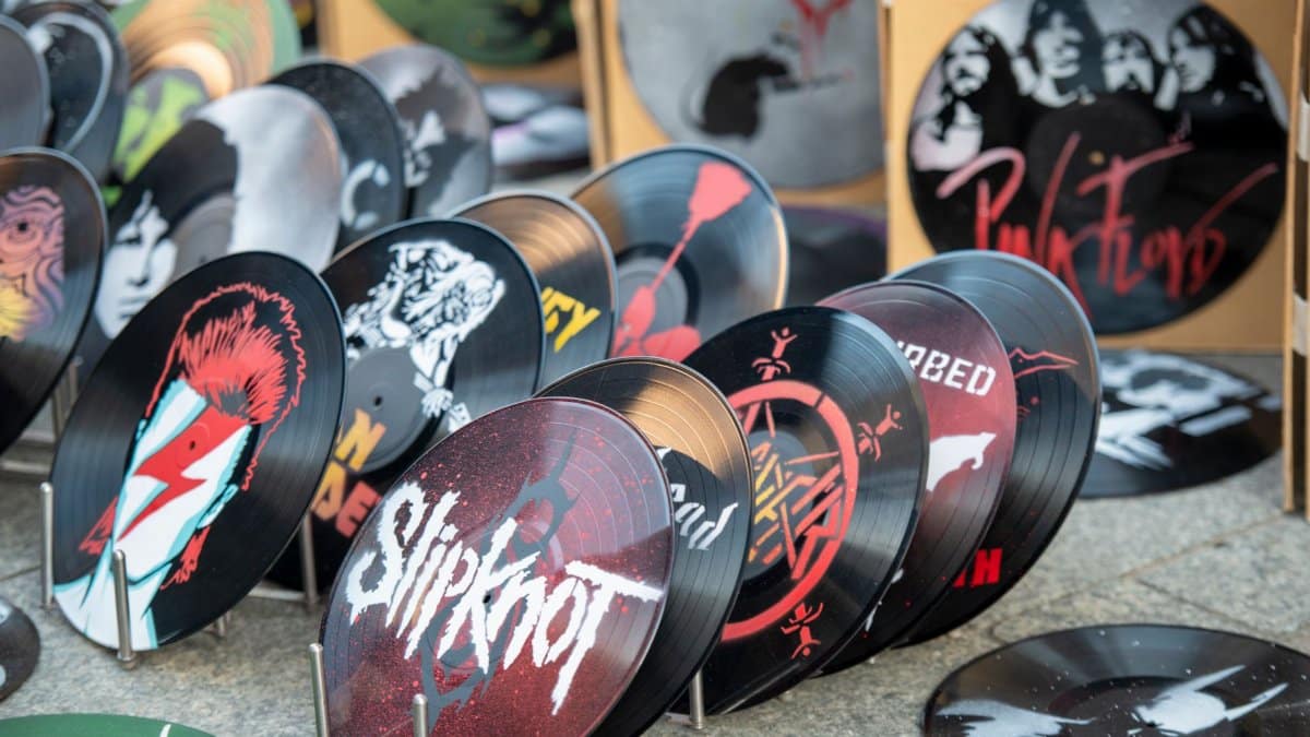 Collection of artistic vinyl records featuring iconic band designs on display at market.
