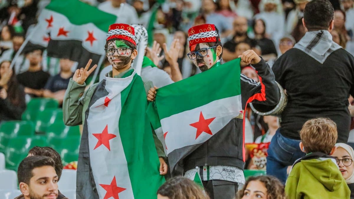 Supporters with Syrian flags at a sports event in Doha, capturing the vibrant and festive spirit.