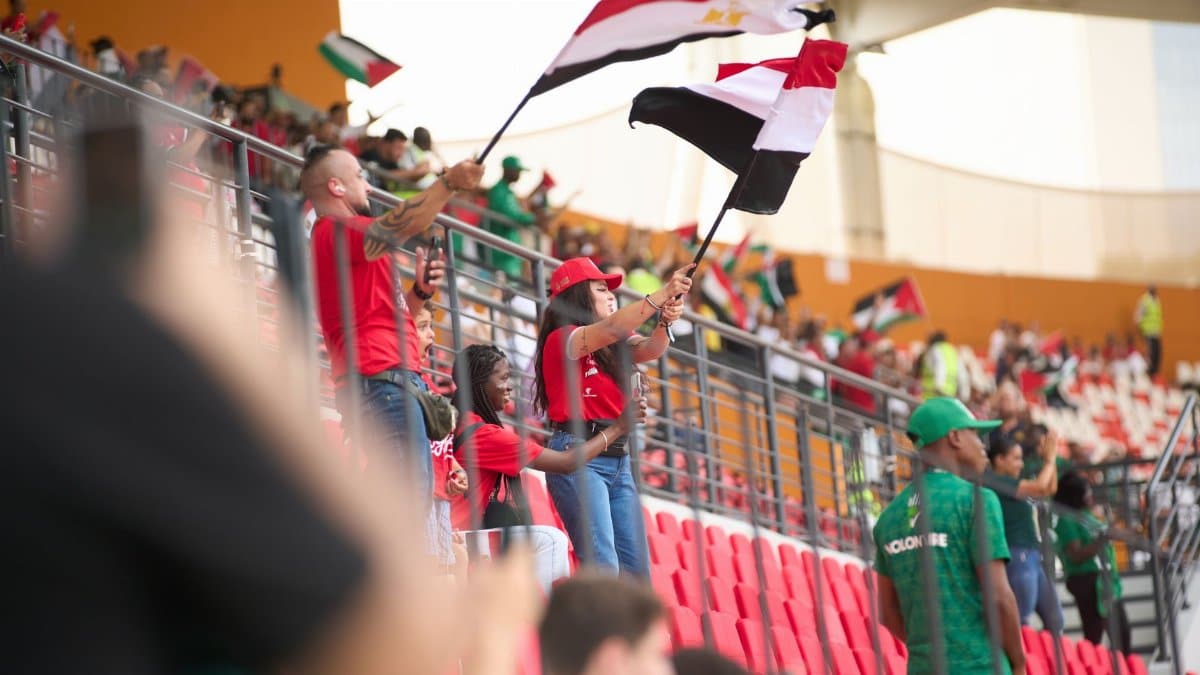 Soccer fans in the stadium wave Egyptian flags, showing their support during a lively sports match.