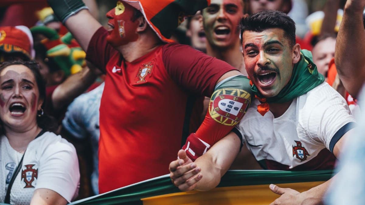 Passionate Portuguese soccer fans celebrating outdoors with flags and face paint.