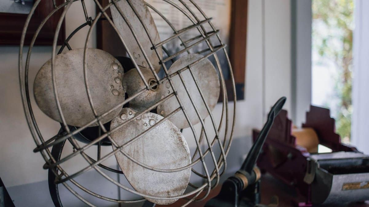 A close-up of a vintage metal fan on a desk with office supplies, creating a nostalgic vibe.