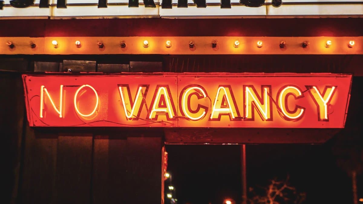 Bright neon 'No Vacancy' sign glowing at night, evoking urban nightlife vibrance.