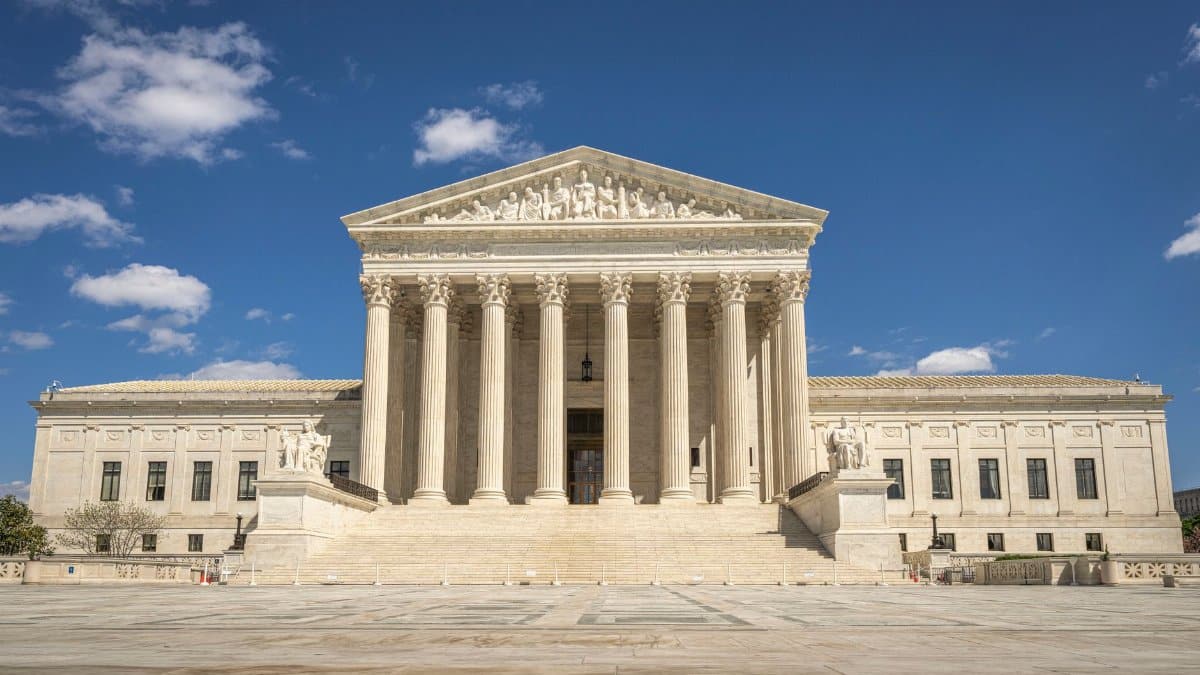 The majestic facade of the United States Supreme Court under a clear blue sky.