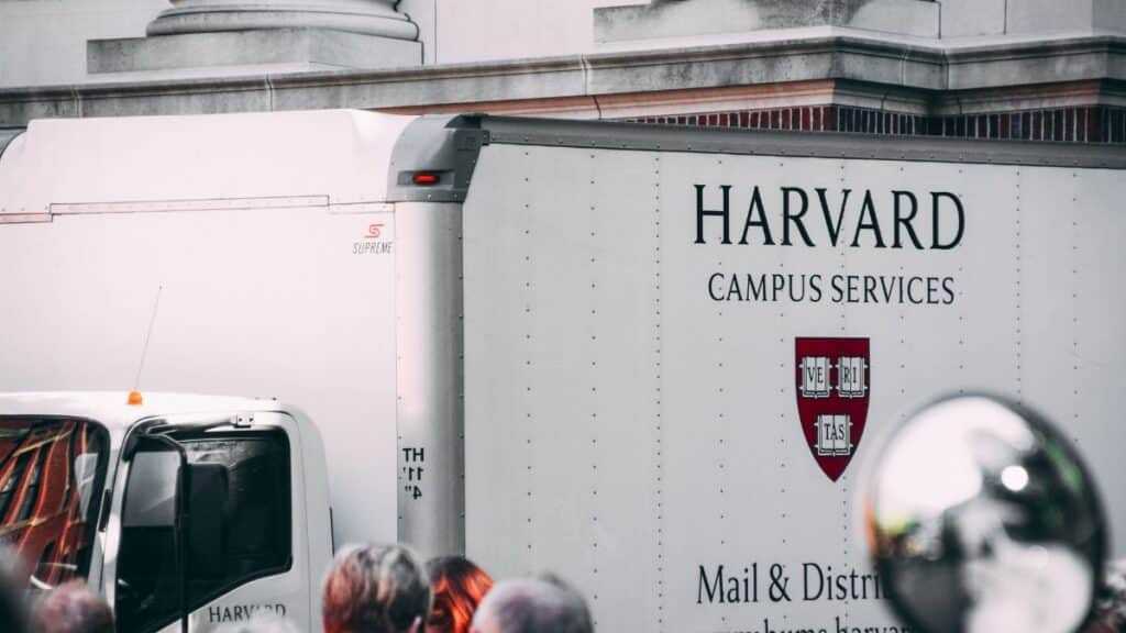 Harvard Campus Services truck in city street, showcasing delivery near university building.