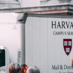 Harvard Campus Services truck in city street, showcasing delivery near university building.