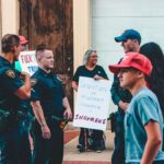 Street protest in Wheeling, WV highlighting immigration issues with signs and police presence.