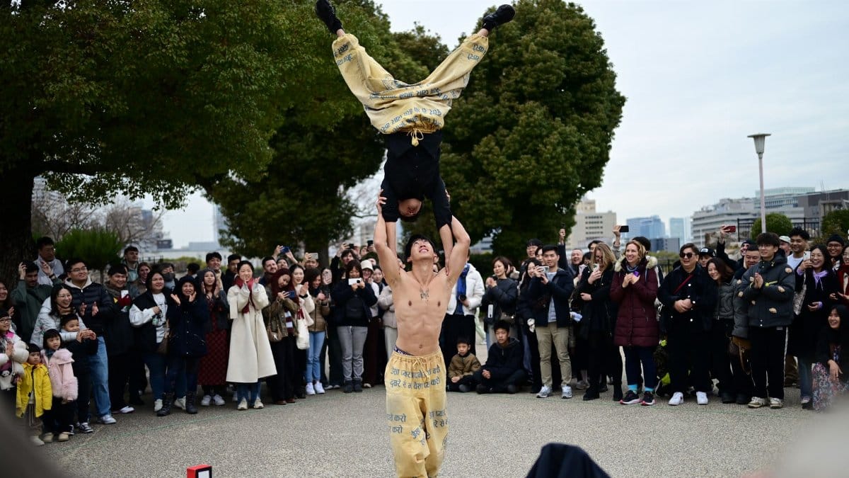 Acrobatic performers captivating an outdoor audience with skillful stunts in a lively street show.