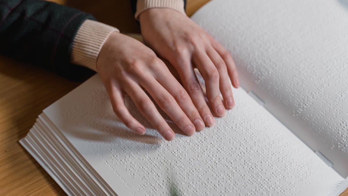 Close-up of hands reading Braille, symbolizing independence and accessibility for the visually impaired.