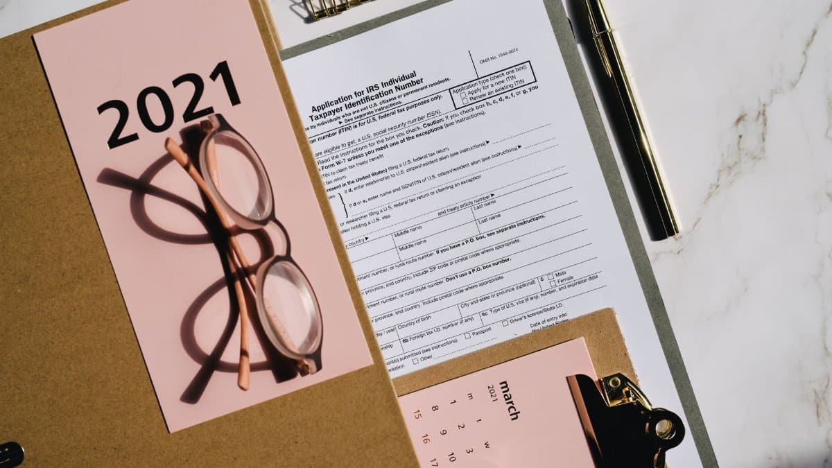 Flat lay of tax forms, calendar, and glasses for 2021 financial planning.
