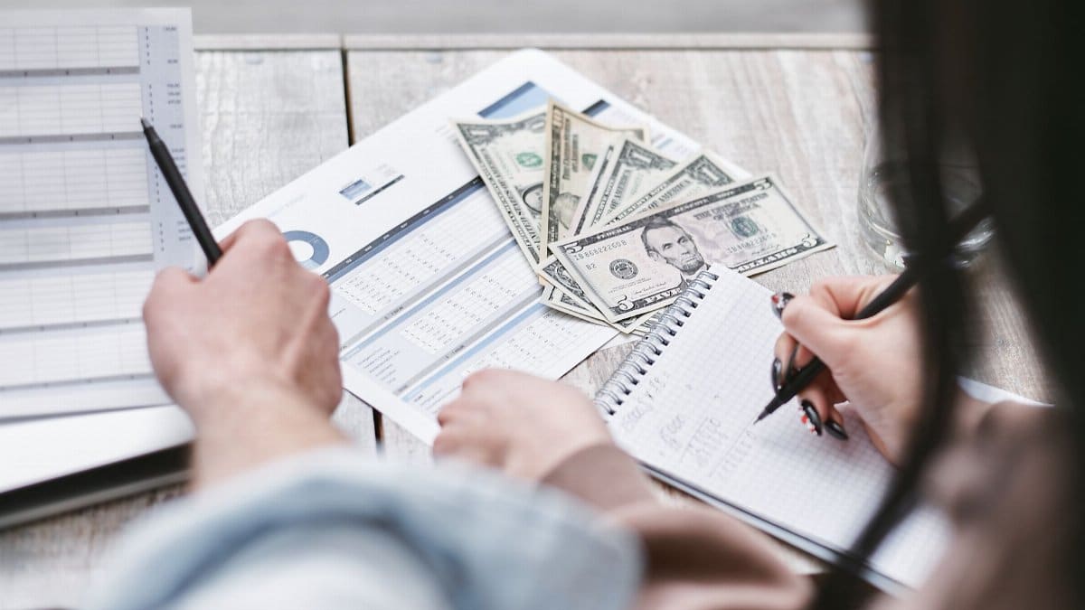 Two people working on financial documents and dollar bills for budgeting.