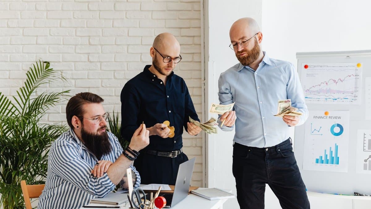 Three business colleagues discussing financial strategies and reviewing charts in a modern office.