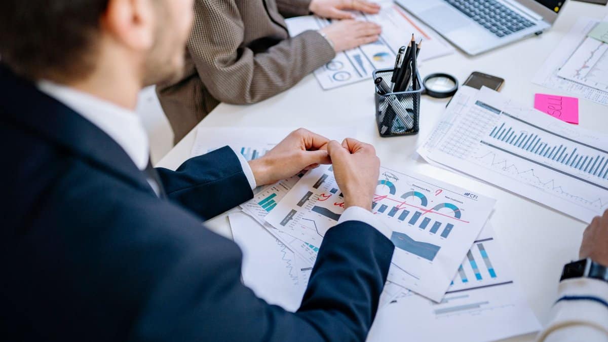 Business team analyzing financial graphs at a meeting table, fostering collaboration in an office environment.