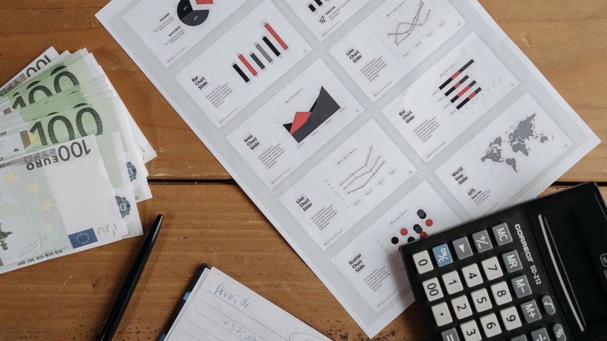 Euro banknotes, graphs, and calculator on a wooden table setup for financial analysis.