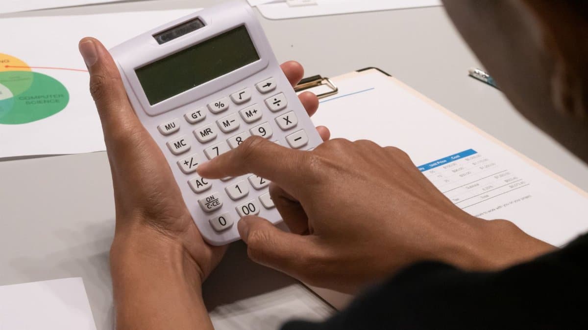 Focused image of a person using a calculator amidst financial documents and charts.