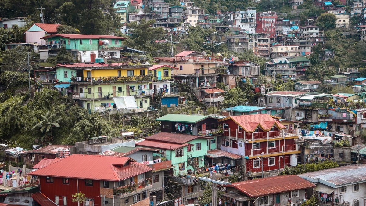 A vibrant hillside residential area in Baguio City, showcasing colorful houses nestled among lush greenery.