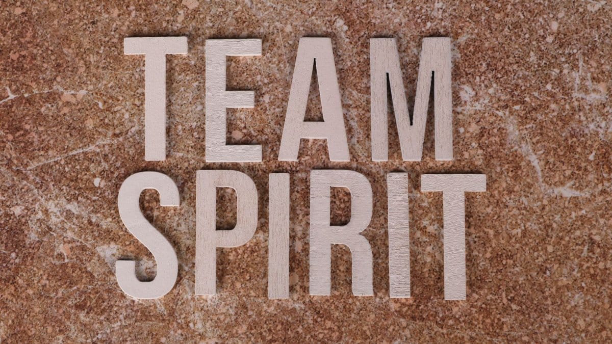 Wooden letters spelling 'Team Spirit' on a textured stone surface, symbolizing collaboration.