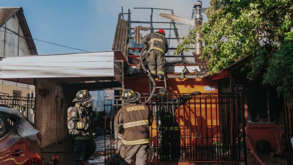 Firefighters working to extinguish a house fire, showcasing bravery and teamwork outdoors.