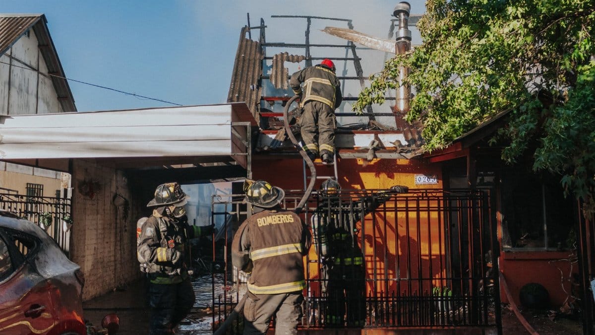 Firefighters working to extinguish a house fire, showcasing bravery and teamwork outdoors.