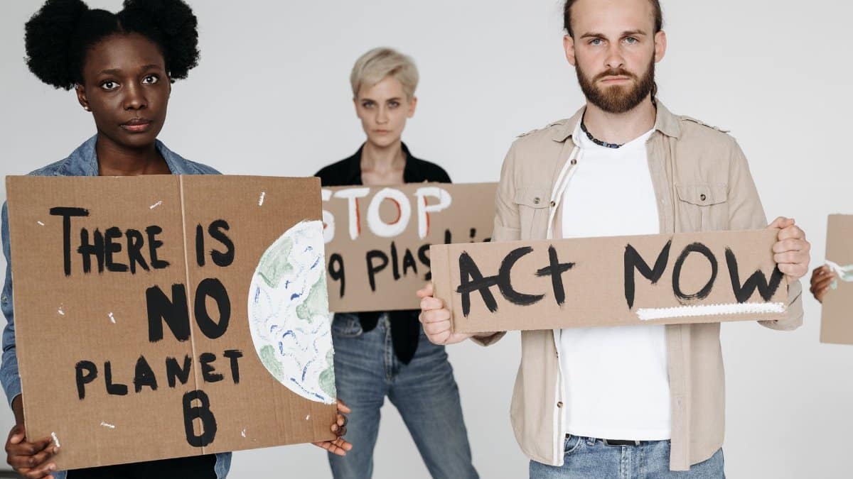 Activists hold cardboard signs advocating for environmental protection and climate action.