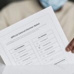A person wearing a face mask holds an official general election ballot.