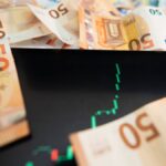Close-up of 50 euro banknotes with a digital stock market chart on a tablet, depicting financial growth.