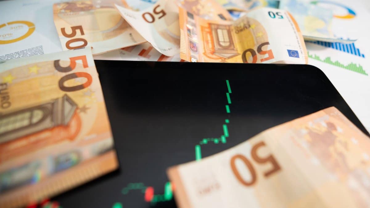Close-up of 50 euro banknotes with a digital stock market chart on a tablet, depicting financial growth.