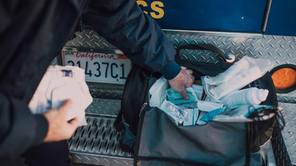 A first responder accessing medical supplies from a bag beside an emergency vehicle.