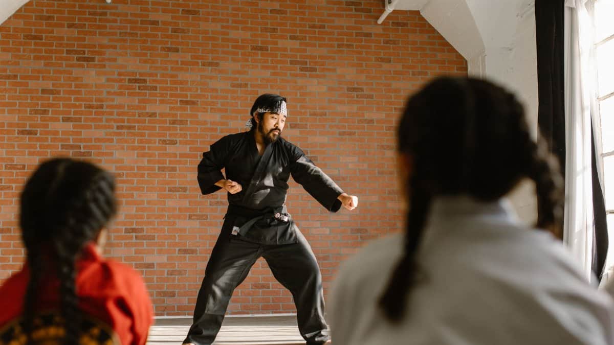 Martial arts instructor demonstrating moves to young students in a training dojo.