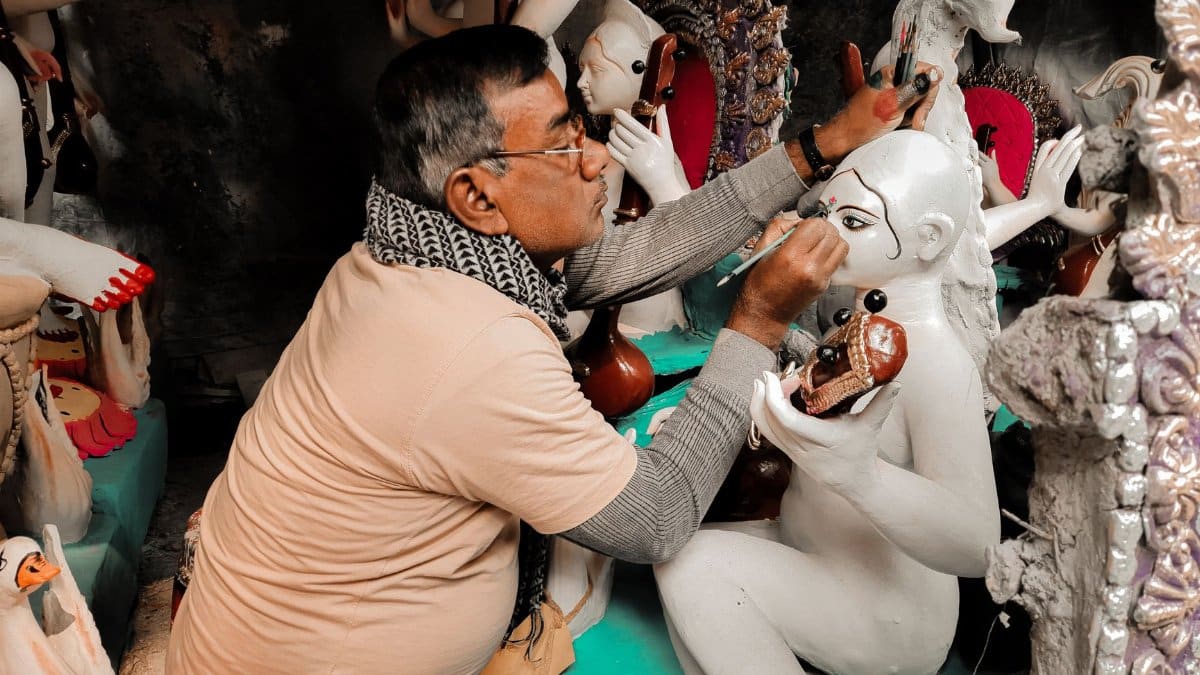 A skilled artist paints intricate details on traditional clay sculptures for cultural festivities.
