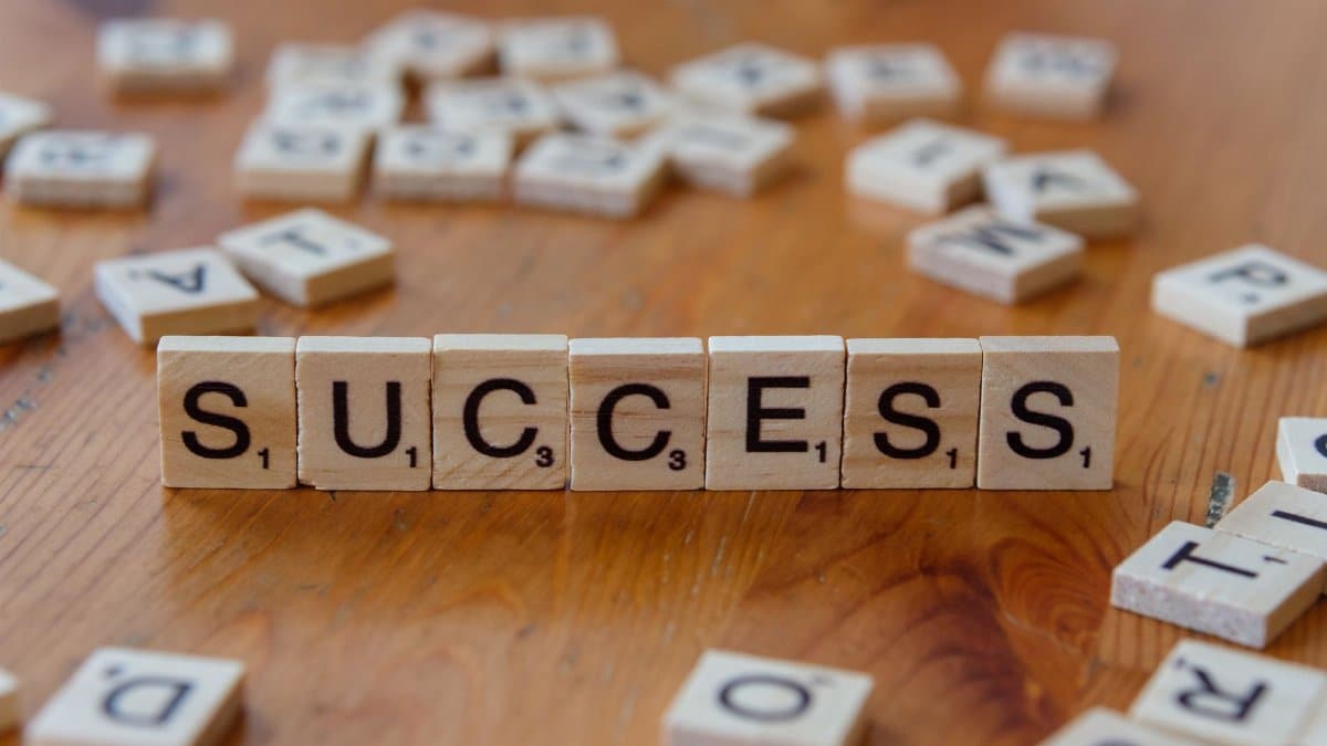 Wooden letter tiles spelling 'success' on a scattered background, symbolizing achievement.