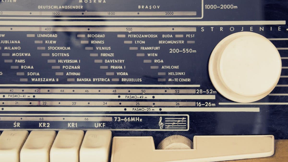 A detailed view of a vintage radio's tuning dial with city stations displayed.