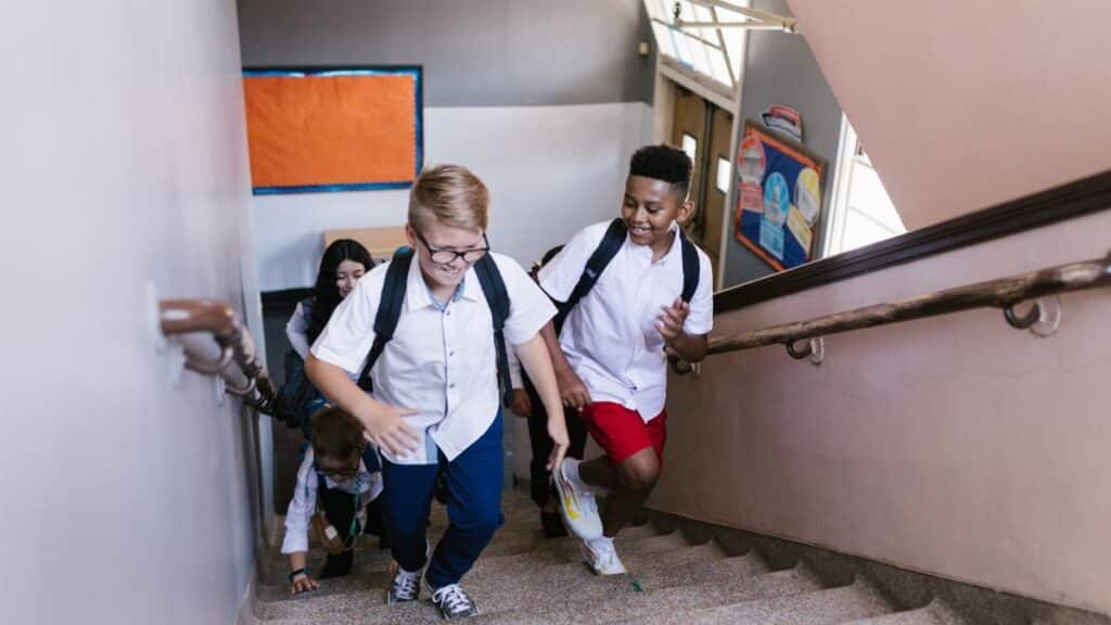 Lively group of students climbing school stairs, carrying backpacks and smiling.