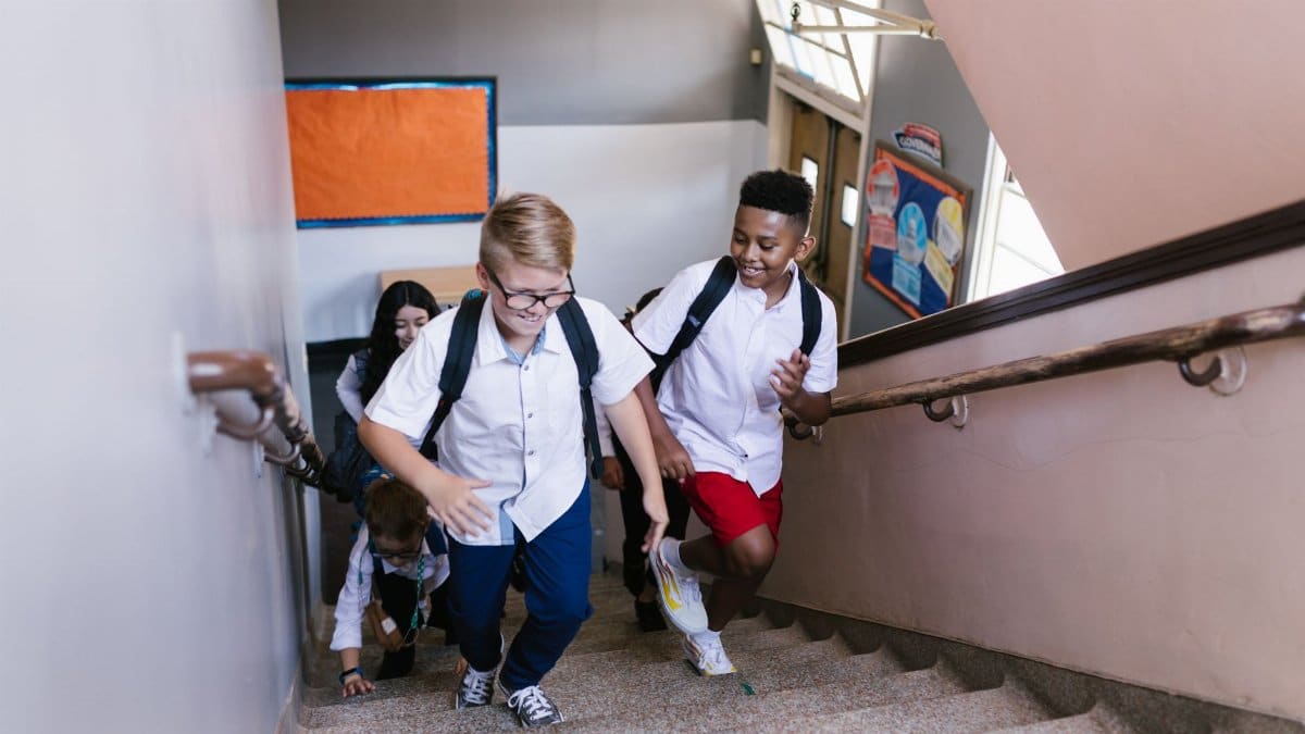 Lively group of students climbing school stairs, carrying backpacks and smiling.