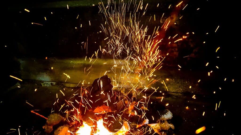 Vivid flames and sparks from burning wood create a dynamic fire scene, highlighting warmth and energy.