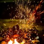Vivid flames and sparks from burning wood create a dynamic fire scene, highlighting warmth and energy.