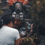 A man and woman engage in ritualistic dance, showcasing vibrant feathered headdress and traditional attire.