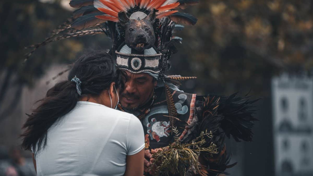 A man and woman engage in ritualistic dance, showcasing vibrant feathered headdress and traditional attire.
