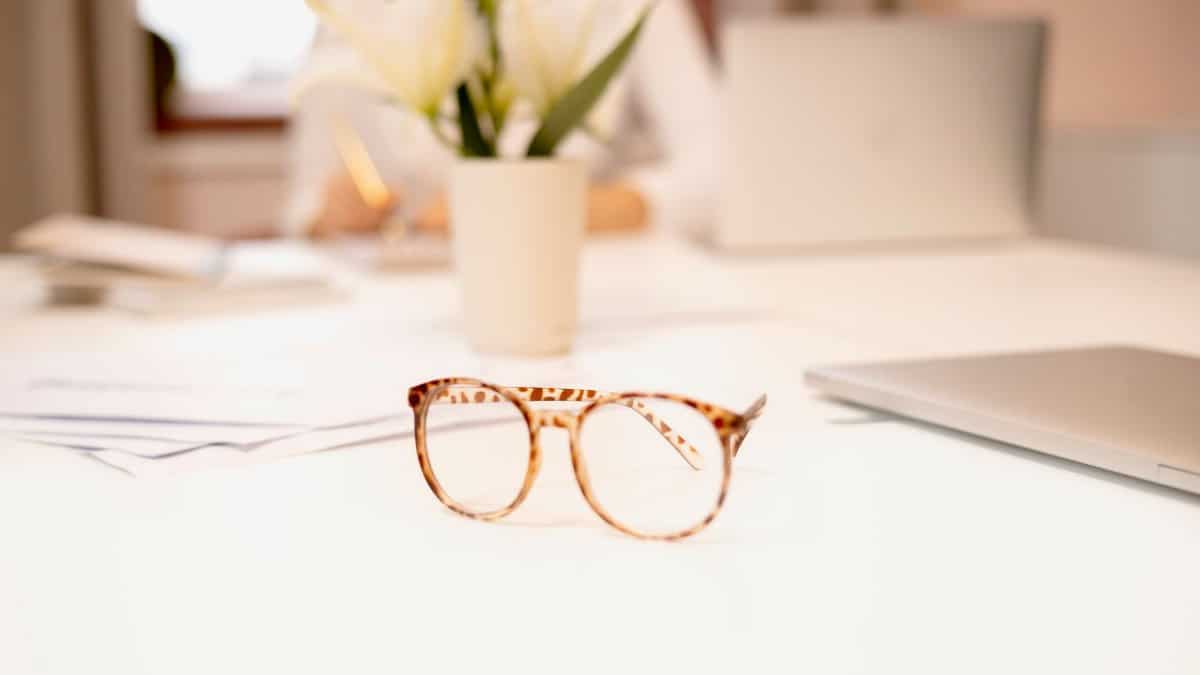 Close-up of fashionable eyeglasses on a bright white desk with blurred background, perfect for office themes.