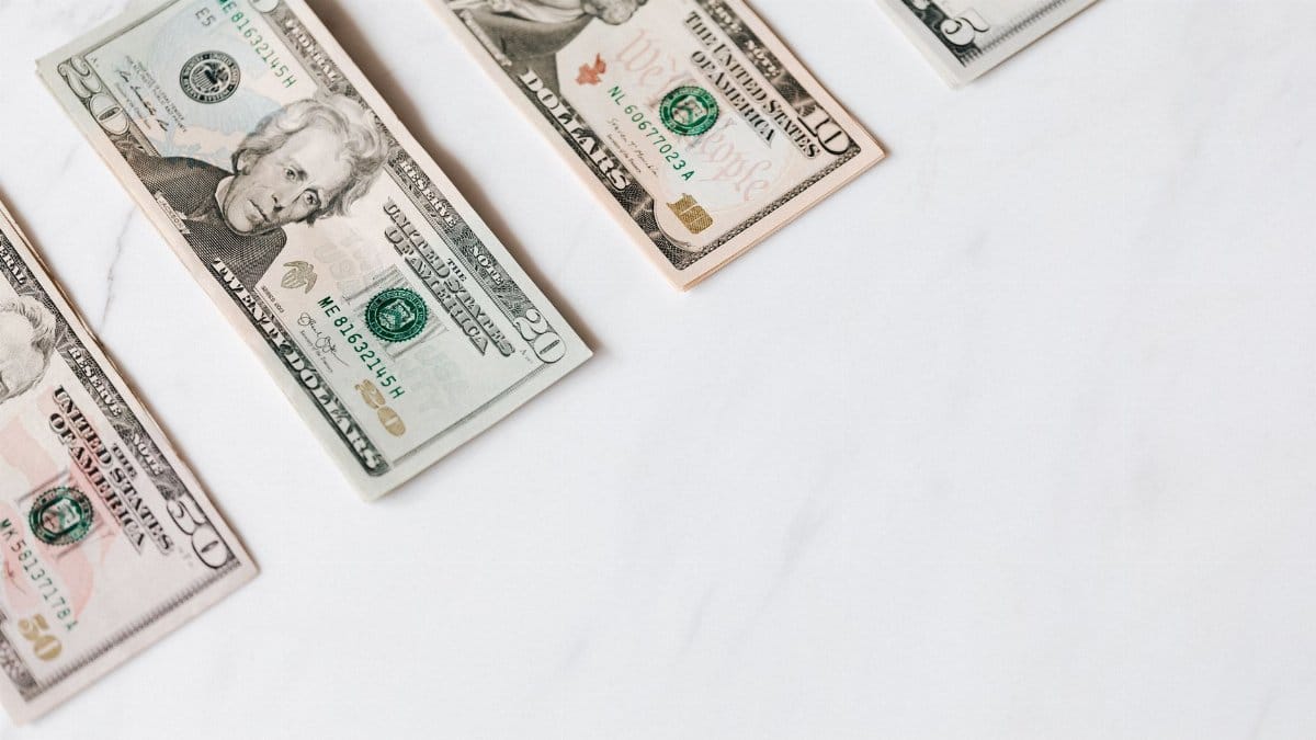 From above of US dollar banknotes in different denominations placed in row on white surface