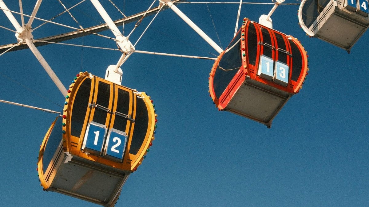 Close-up of vibrant Ferris wheel cabins numbered 12 and 13 against a clear blue sky.