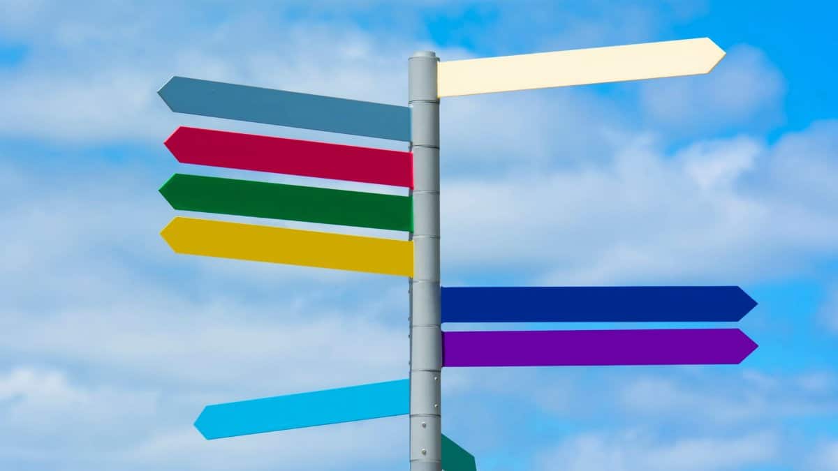 Multicolored directional signpost against a vibrant blue sky, offering guidance.