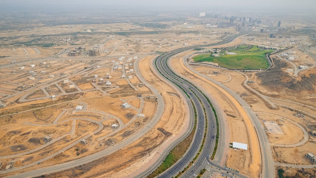 Wide aerial view of a developing desert highway with surrounding construction sites.